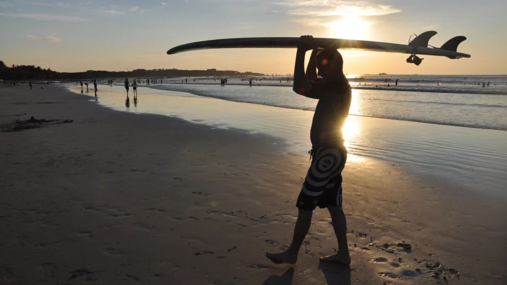 Beach visitor carrying a surfboard at Tamarindo Beach